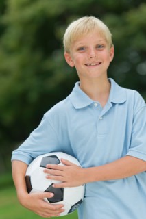 Boy (10-11) holding soccer ball.