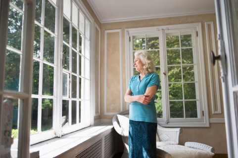 Senior woman looking through window.
