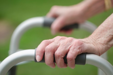 Senior walking with walker, close-up of hands.