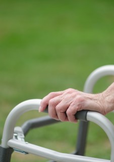 Senior walking with walker, close-up of hands.