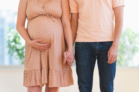 Pregnant woman holding partner's hand.