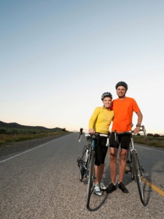 Couple of cyclists posing for portrait on empty road.
