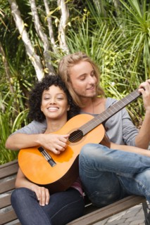Young couple in park, man playing guitar. Photo : Rob Lewine
