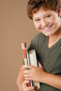 Studio portrait of boy (12-13) holding books. Photo : Rob Lewine
