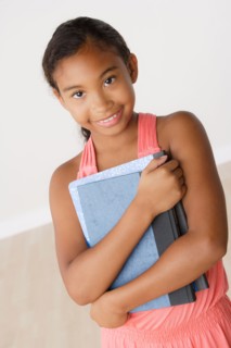 Studio portrait of girl (8-9) holding books. Photo : Rob Lewine
