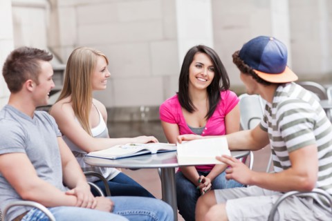 Four college students sitting at cafe table. Photo : Take A Pix Media