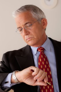 Studio portrait of senior businessman checking time. Photo : Rob Lewine