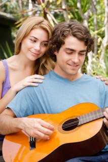 Young couple in park, man playing guitar. Photo : Rob Lewine