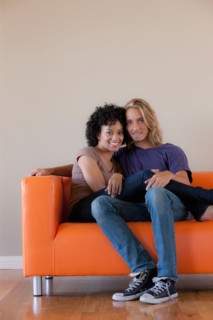Portrait of young couple sitting on sofa. Photo : Rob Lewine