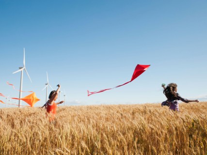 USA, Oregon, Wasco, Girls (10-11, 12-13) playing with kite in wheat field, wind turbines in