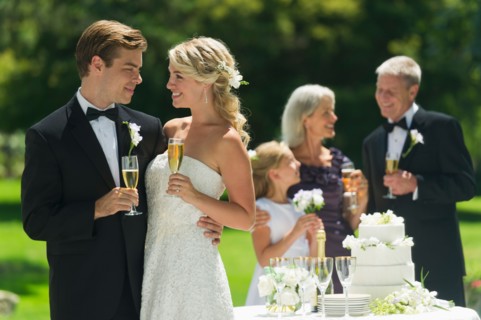 Bride and groom at wedding reception, people in background.