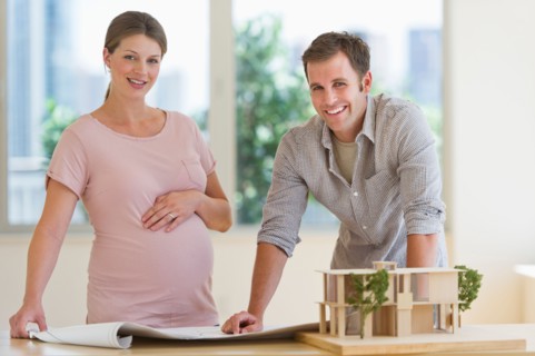 Young couple with blueprints and house model.