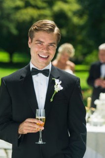 Portrait of groom holding champagne flute.