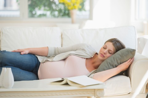 Young pregnant woman sleeping on sofa.