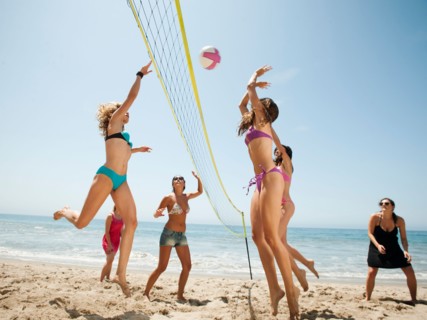 Group of young women playing beach volleyball .