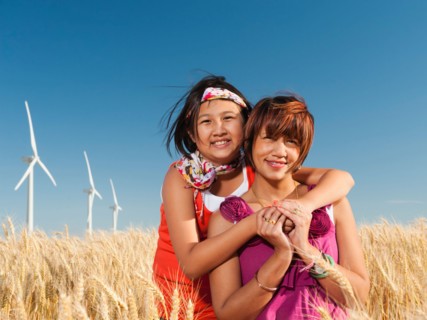 USA, Oregon, Wasco, Girl (10-11) and mother standing in wheat field in front of wind turbines.
