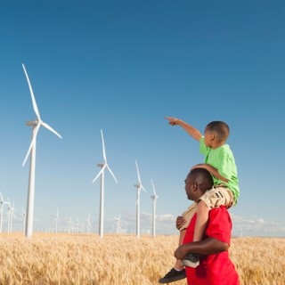 USA, Oregon, Wasco, Boy (8-9) piggy-back riding on father pointing at wind turbines.