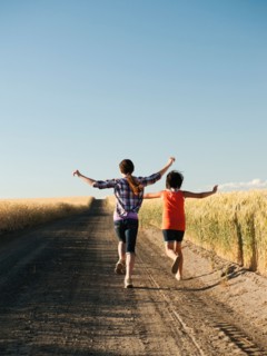 Girls (12-13, 10-11) running along dirt road.