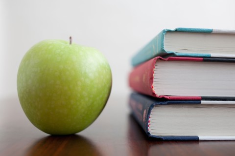 Studio shot of green apple and textbooks. Photo : Winslow Productions