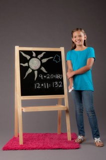 Studio portrait of girl (8-9) standing next to blackboard. Photo : Rob Lewine