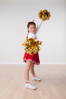 Studio portrait of girl (8-9) cheerleading. Photo : Rob Lewine