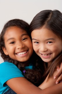 Studio portrait of two girls (8-9) embracing. Photo : Rob Lewine