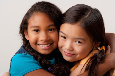 Studio portrait of two girls (8-9) embracing. Photo : Rob Lewine