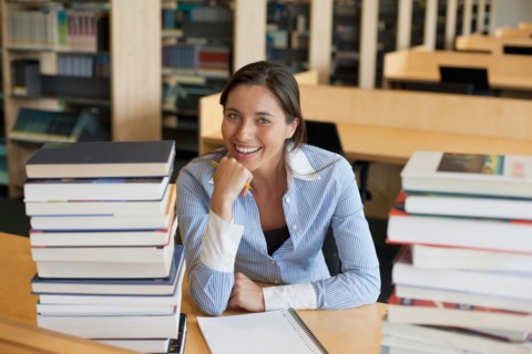 Portrait of female student with books in library. Photo : Jan Scherders