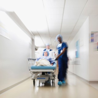 Senior woman being taken to operating room by medical staff.