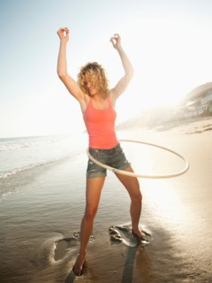 Young attractive woman exercising with hoola hoop.