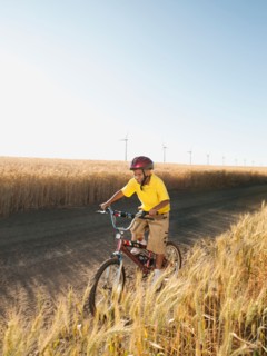 Boy (8-9) cycling along dirt road.