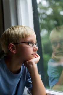 Boy (10-11) looking through window.