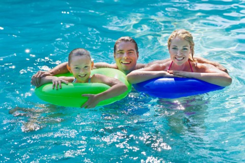 Girl (10-11) with parents in swimming pool.