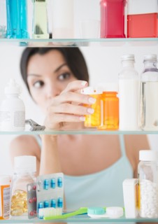 Woman taking medicine from cabinet. Photo: Jamie Grill