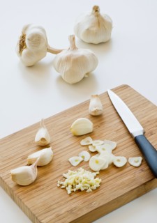 Studio shot of fresh garlic being chopped on cutting board.