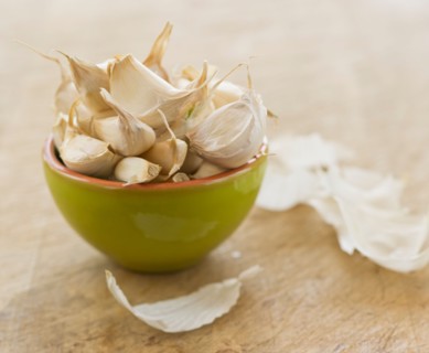 Studio shot of fresh garlic cloves in green bowl.