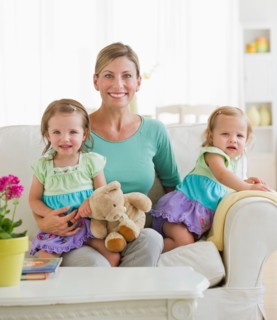 Portrait of mother with daughters (2-3) on sofa.