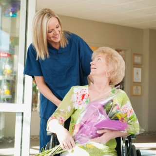 Young nurse pushing senior woman on wheelchair.