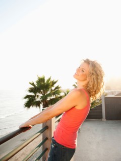 Young attractive woman relaxing on terrace overlooking sea.