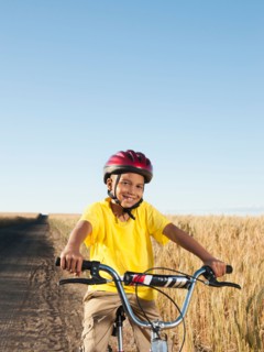Boy (8-9) cycling along dirt road.