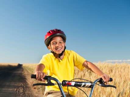 Boy (8-9) cycling along dirt road.