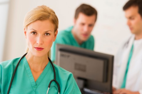 Portrait of female doctor in front of nurse's station.