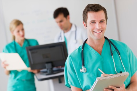 Portrait of male doctor in front of nurse's station.