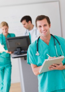 Portrait of male doctor in front of nurse's station.