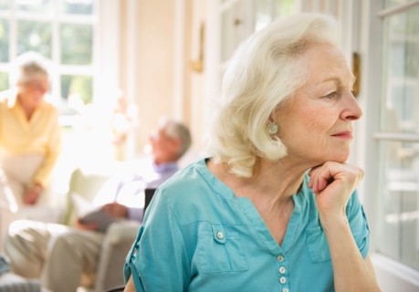 Senior woman looking through window in nursing home.