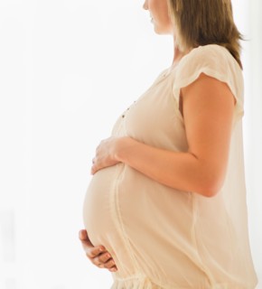 Pregnant woman looking through window.