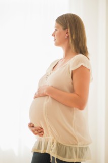 Pregnant woman looking through window.