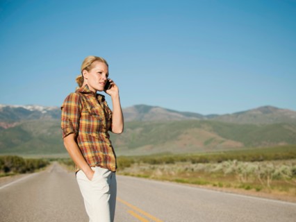 USA, Utah, Kanosh, Mid adult woman calling emergency services on empty desert road.