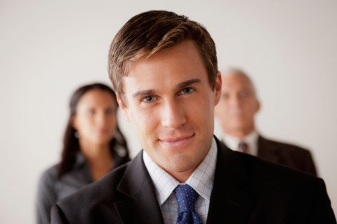 Studio shot of business people, focus on young business man. Photo : Rob Lewine