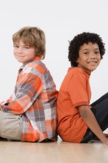 Studio portrait of two boys (8-9) sitting back to back. Photo : Rob Lewine